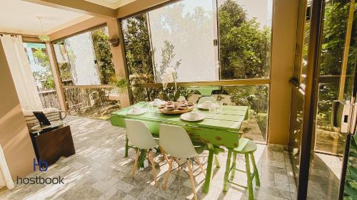 uma mesa verde e cadeiras num quarto com janelas em Casa próxima a praia do pecado - WIFI 200MB - TV Smart - Cozinha equipada - Churrasqueira - Pet friendly - Quintal em Macaé