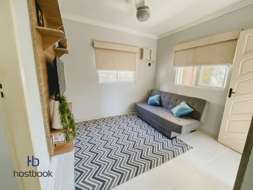 uma sala de estar com um sofá azul e um tapete em Casa próxima a praia do pecado - WIFI 200MB - TV Smart - Cozinha equipada - Churrasqueira - Pet friendly - Quintal em Macaé