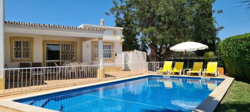 a pool with chairs and an umbrella next to a house at Casa Dos Cedros in Guia