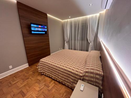 a small bedroom with a bed and a tv at San Raphael Hotel in São Paulo