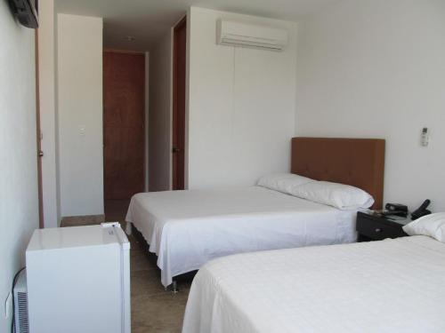 a hotel room with two beds with white sheets at Hotel Kariary in Puerto Boyacá