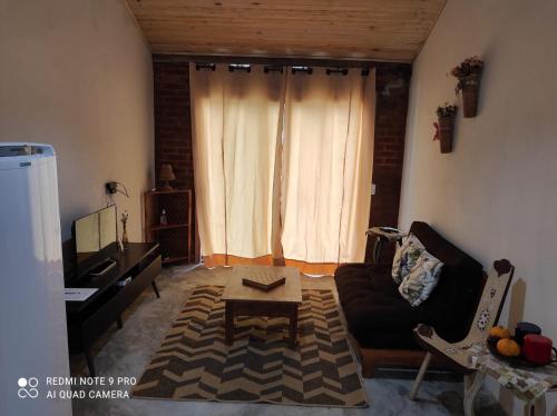 uma sala de estar com um sofá e uma mesa em Chalé Lavanda com Hidro, Trilhas e Cachoeiras em São Francisco Xavier