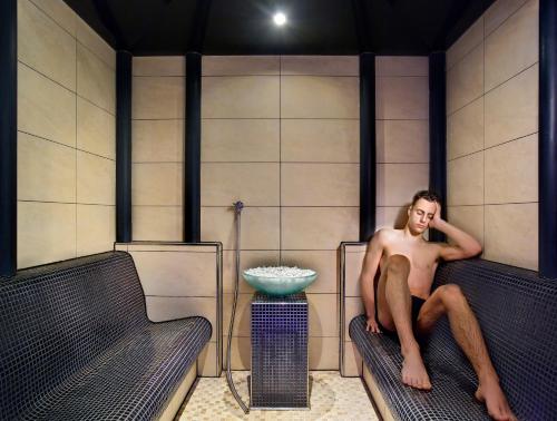 a man sitting on a bench in a bath room at Hotel Sassella in Grosio