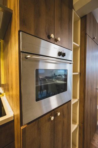 a stainless steel oven in a kitchen with wooden cabinets at Museum Apartment in Subotica