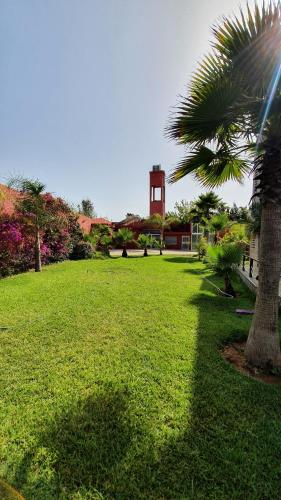 a palm tree and a clock tower in a park at Belle maison de campagne in Kenitra