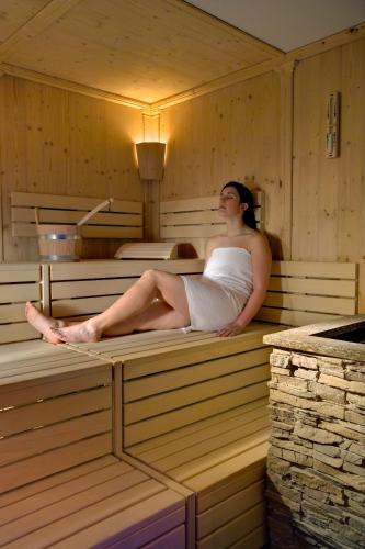a woman is sitting in a sauna at Hotel Sassella in Grosio