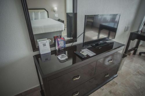 een slaapkamer met een dressoir met een spiegel en een bed bij Best Western Plus Tuxtepec in San Juan Bautista Tuxtepec