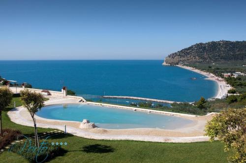 a swimming pool next to a beach and the ocean at Hotel Residence Il Porto in Mattinata