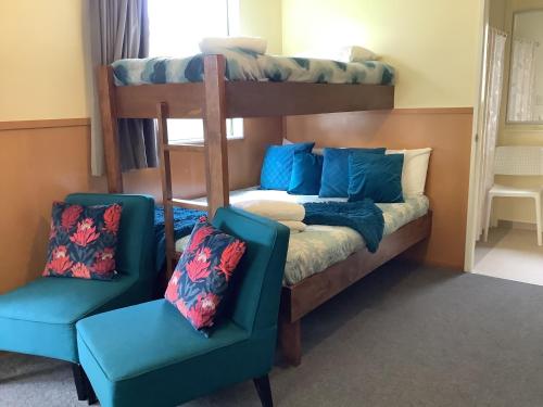 a bedroom with two bunk beds and two chairs at Glenmark Holiday Park in Timaru