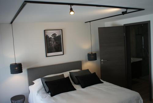 um quarto com uma cama branca e almofadas pretas em Les hôtes voies em Bouillon