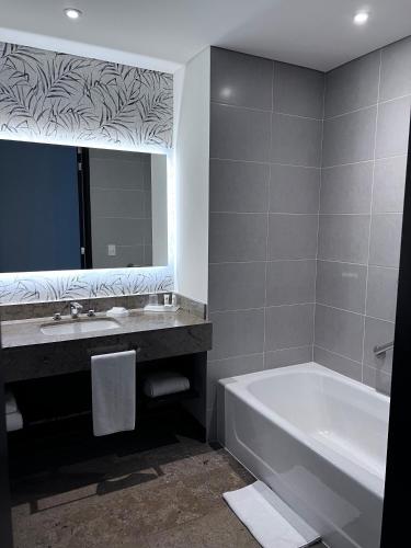 a bathroom with a tub and a sink and a mirror at Holiday Inn Bogota Airport by IHG in Bogotá