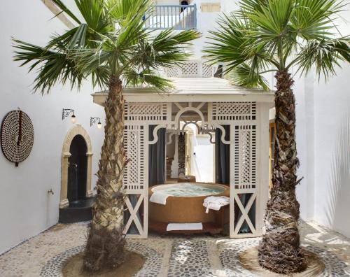 a bedroom with two palm trees in front of a bed at Riad Baladin in Essaouira