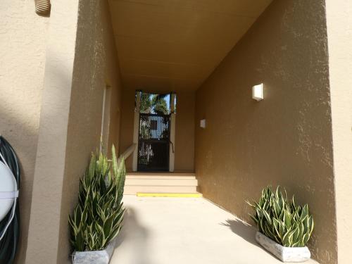 a hallway with two potted plants in front of a door at Beachside Bungalow: Surfside I #104 in South Padre Island