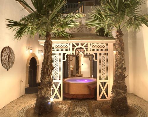 a bathroom with a tub and two palm trees at Riad Baladin in Essaouira