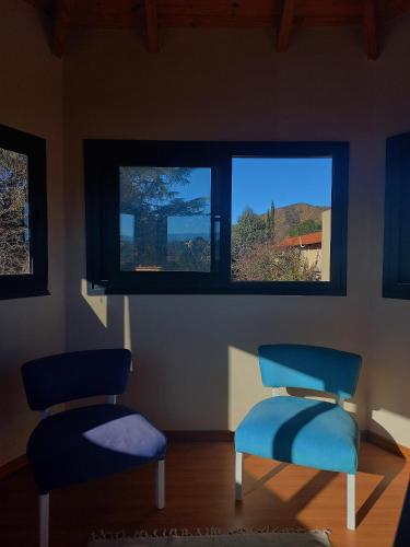 two blue chairs in a room with a window at Posada Faro Serrano in Villa General Belgrano