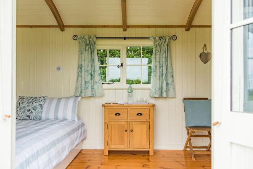 a bedroom with a bed and a dresser and a window at Mist Sheperd's Hut by Bloom Stays in Egerton