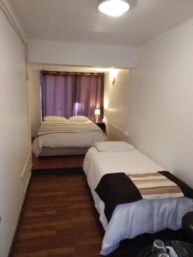 ビーニャデルマールにあるHostal Casamar-Viñaの窓付きの小さな部屋のベッド2台