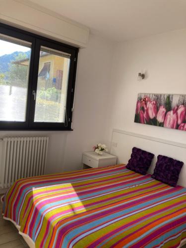 a bedroom with a bed with a colorful striped blanket at Casa Lisa in Lenno