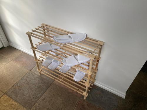 a group of white slippers on a wooden rack at DELIGHTFUL AND CHARMING ROSE COTTAGE in Kilmore