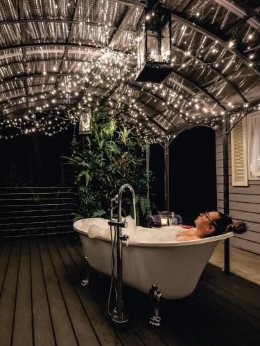 a woman laying in a bath tub on a deck with lights at Aldgate Valley Bed and Breakfast in Aldgate