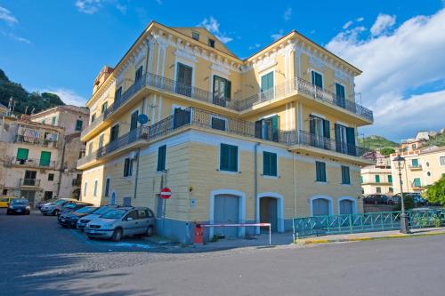duży żółty budynek z samochodami zaparkowanymi przed nim w obiekcie Palazzo Della Monica w mieście Vietri sul Mare