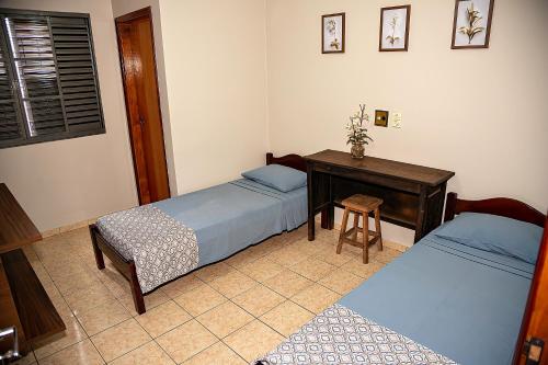 a bedroom with two beds and a desk and a table at RP HOTEL in Ribeirão Preto