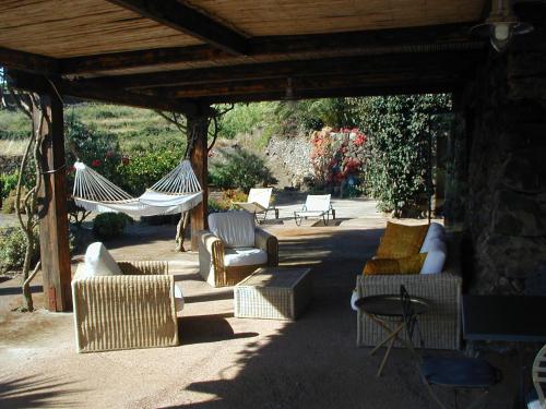eine Terrasse mit Sofas und Hängematten unter einem Pavillon in der Unterkunft Holiday home Dammuso Magia in Pantelleria