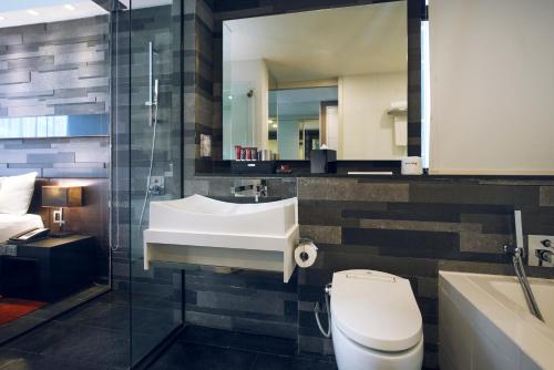 a bathroom with a sink and a toilet and a mirror at Quincy Hotel Singapore by Far East Hospitality in Singapore