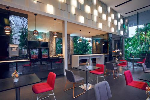 シンガポールにあるQuincy Hotel Singapore by Far East Hospitalityの赤い椅子とテーブルのあるレストラン、バー
