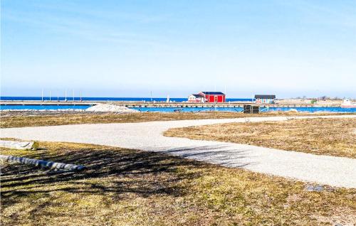 a walkway leading to a beach with a red building at Stunning Home In Degerhamn With Kitchen in Degerhamn