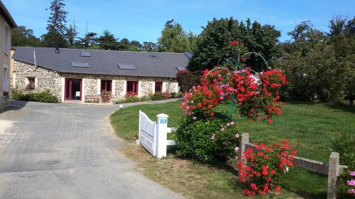 a house with a white fence and red flowers at Gîte - La Rigaudière in Le Theil-de-Bretagne