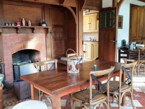 une cuisine avec une table en bois et une cheminée dans l'établissement Retraite Paisible au Cœur de la Forêt de Rambouillet avec Étang Privé et Charme Authentique - FR-1-527-8, à Clairefontaine