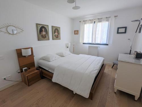 a white bedroom with a bed and a window at Appartement Arcachon, 2 pièces, 2 personnes - FR-1-420-90 in Arcachon
