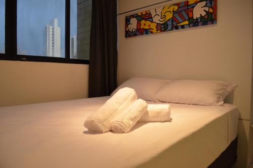 1 cama con 2 toallas y ventana en Goldenland Home Service, en Recife