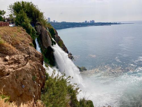 a waterfall on the side of a mountain next to the water at Karden Otel in Antalya