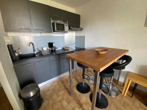 une petite cuisine avec une table en bois et un four micro-ondes dans l'établissement Appartement pour 4 pers, proche plage, parking, terrasse, commerces à proximité - FR-1-81-559, à La Franqui-Plage