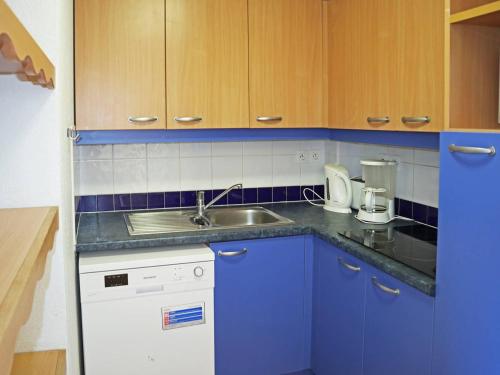 une cuisine avec des armoires bleues et un évier dans l'établissement Appartement skis aux pieds avec piscine intérieure, proche services - FR-1-322-478, aux Orres