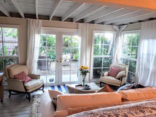 een woonkamer met een bank, stoelen en ramen bij Chateau Gardens in Lake Worth