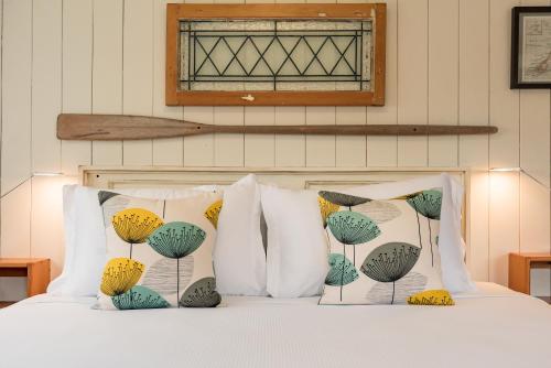 a bed with four pillows and a window above it at Arcadia Lodge Russell in Russell