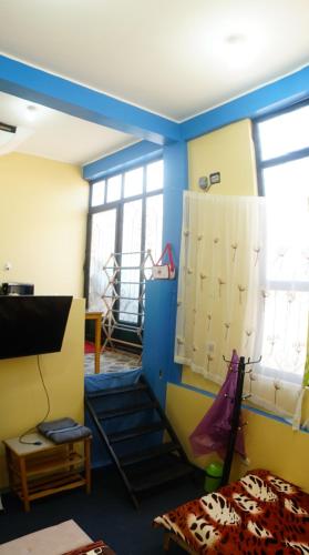 Habitación con ventanas y paredes de color azul y amarillo. en Huascarán wasi, cómodo, con wifi y ducha caliente, en Huaraz
