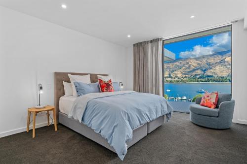 a bedroom with a bed and a chair and a large window at Luxurious Lakefront Penthouse in Wanaka