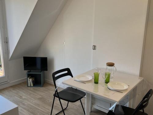 une table blanche avec deux chaises et une télévision dans l'établissement Appartement 2 pièces en bord de mer avec accès direct à la plage de Cabourg, proche Thalassothérapie - FR-1-487-336, à Cabourg