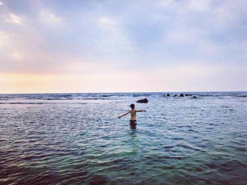 a person standing in the water in the ocean at Xiaoliuqiu Happy House B&B in Xiaoliuqiu