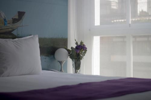 a bed with a vase of flowers next to a window at Infinito Hotel in Buenos Aires