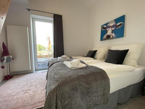 a bedroom with a large bed and a window at Kuh Blick Ferienhaus Sehestedt in Sehestedt