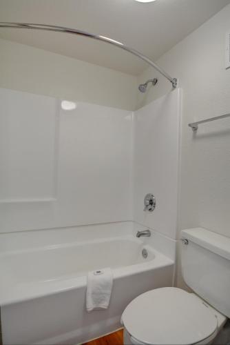 a white bathroom with a toilet and a bath tub at Motel 6-Chicopee, MA - Springfield in Chicopee