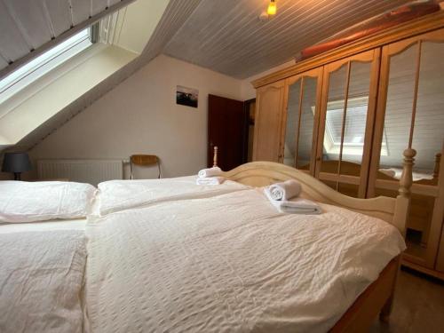 une chambre avec un grand lit avec des draps blancs dans l'établissement Strandlöper Ferienhaus, à Dangast