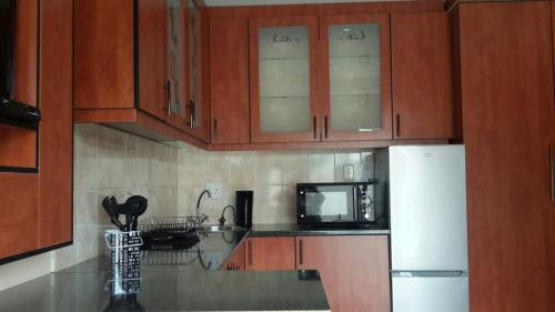 a kitchen with wooden cabinets and a white refrigerator at Genie's Nest 2 in Pretoria