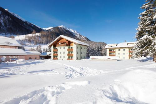 a snow covered parking lot in front of a hotel at Reka-Feriendorf Bergün in Bergün