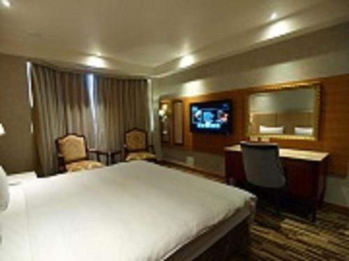 a hotel room with a large bed and a television at Grace Hotel in Taipei